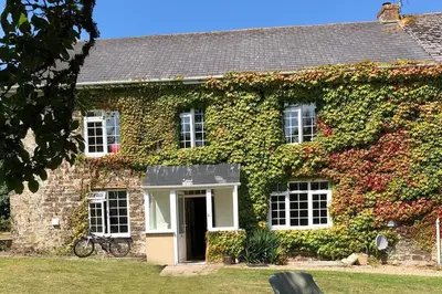 a building covered in ivy with a bike in front of it at The Farmhouse, Fowey in Fowey
