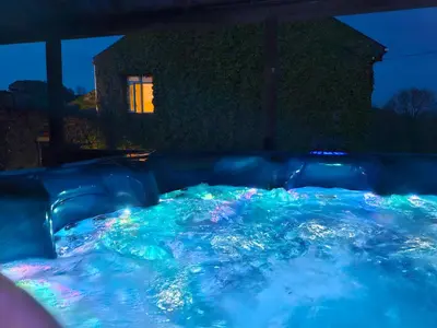 a hot tub with lights in front of a house at The Farmhouse, Fowey in Fowey