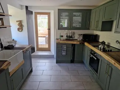 a kitchen with green cabinets and a tile floor at The Farmhouse, Fowey in Fowey
