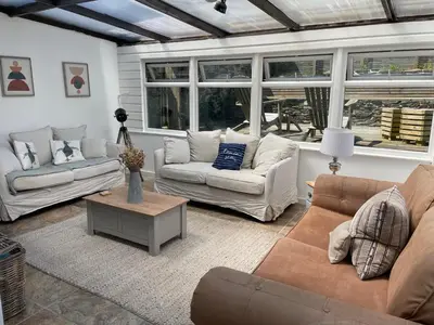 a living room with two couches and a table at The Farmhouse, Fowey in Fowey