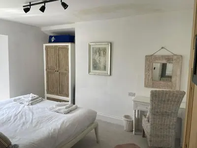 a bedroom with a bed and a mirror and a chair at The Farmhouse, Fowey in Fowey