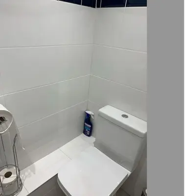 a white bathroom with a toilet and a sink at Cornwall - Unique two storey barn in St Austell