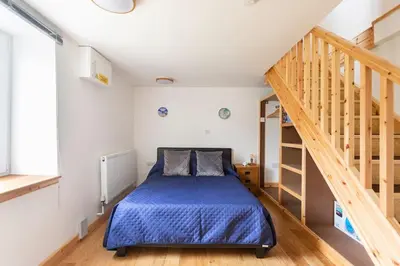 a bedroom with a bed in a room with stairs at Cornwall - Unique two storey barn in St Austell
