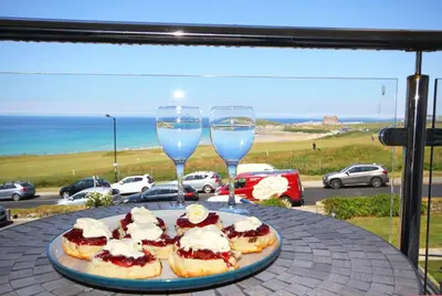 a plate of food on a table with two glasses of wine at 7 Ocean Gate in Newquay