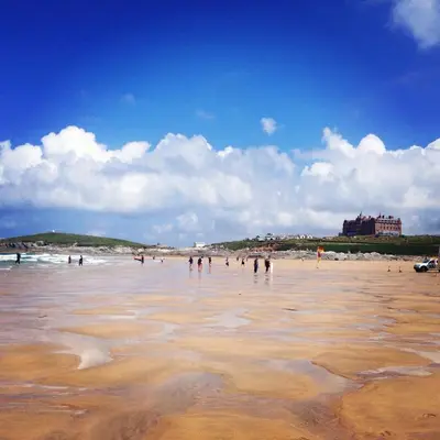 a group of people standing in the water on a beach at 7 Ocean Gate in Newquay