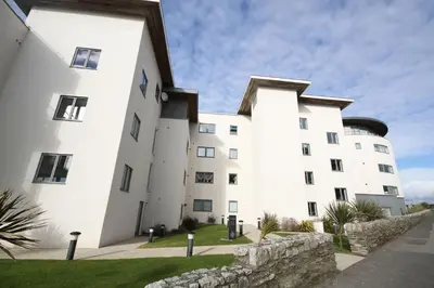 a large white building with a stone wall at 7 Ocean Gate in Newquay