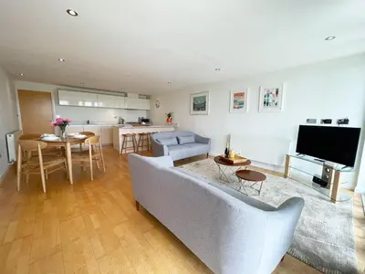 a living room with a couch and a tv and a kitchen at 8 Zinc in Newquay