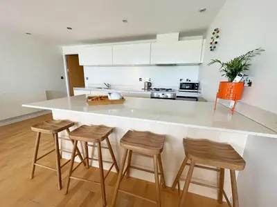 a kitchen with a counter and four stools at 8 Zinc in Newquay