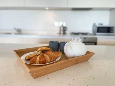 a plate of croissants and a tea pot on a wooden tray at 8 Zinc in Newquay