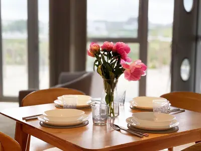 a table with plates and a vase of pink flowers at 8 Zinc in Newquay