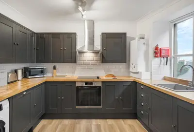 a kitchen with black cabinets and wooden counter tops at Harbour Steps in Falmouth