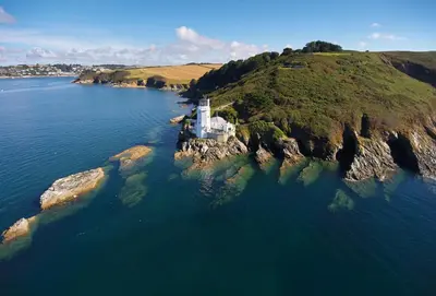 an island in the water with a lighthouse on it at Harbour Steps in Falmouth