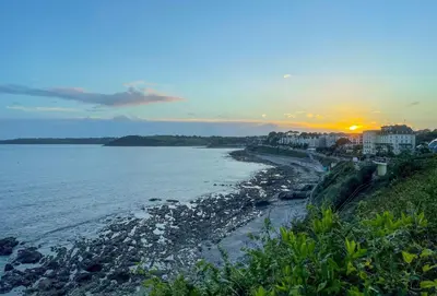 a view of a beach with the sunset in the background at Harbour Steps in Falmouth