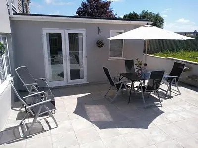 a patio with a table and chairs and an umbrella at Sandy cottage, nr Eden & beaches in St Austell