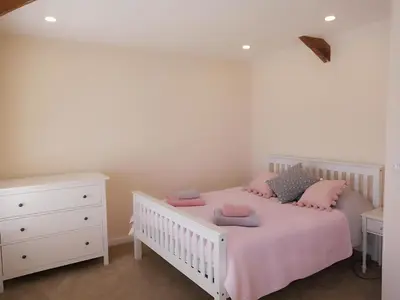 a bedroom with a white crib with pink pillows at Sandy cottage, nr Eden & beaches in St Austell