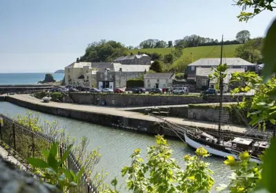 a boat docked in a marina next to a town at Sandy cottage, nr Eden & beaches in St Austell
