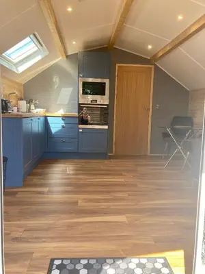a kitchen with blue cabinets and a wooden floor at Laity's Lodge in Penzance