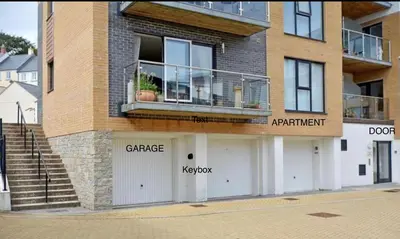 a building with two garage doors and a balcony at Stunning Apartment, balconies, private beach, coast path in Charlestown