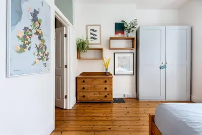 a bedroom with a bed and a wooden dresser at Treetops - Characterful flat with parking, close to beach in Falmouth