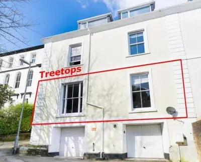 a white building with a tigers sign on it at Treetops - Characterful flat with parking, close to beach in Falmouth