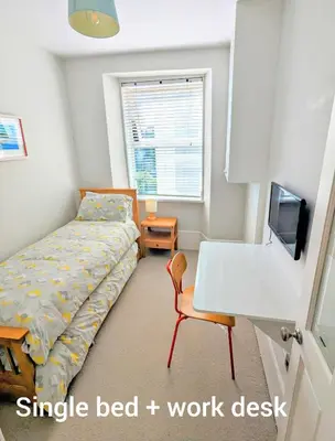 a bedroom with a bed and a desk and a tv at Pendennis - Bright Victorian flat, sea views & close to beach in Falmouth