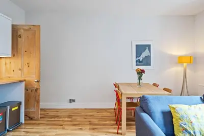 a living room with a table and a blue couch at Pendennis - Bright Victorian flat, sea views & close to beach in Falmouth