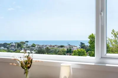 a window with a view of the ocean at Manacles - Spacious flat near beach with sea views & parking in Falmouth