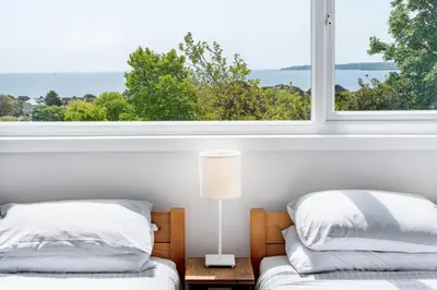 a bedroom with two beds and a large window at Manacles - Spacious flat near beach with sea views & parking in Falmouth