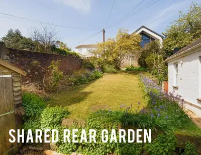 a garden with a shaded rear garden with the words shared rear garden at Manacles - Spacious flat near beach with sea views & parking in Falmouth