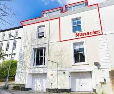 a white building with a sign that reads manabases at Manacles - Spacious flat near beach with sea views & parking in Falmouth