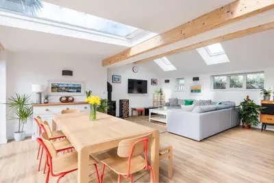 a living room with a table and a couch at Trevint - Modern beach house in Falmouth near beach, private garden and parking in Falmouth