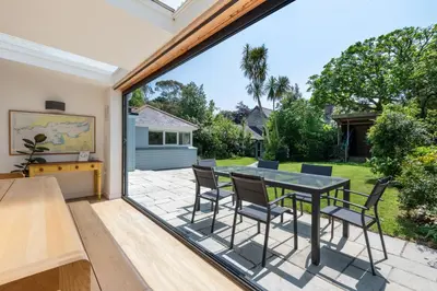 a dining room with a table and chairs on a patio at Trevint - Modern beach house in Falmouth near beach, private garden and parking in Falmouth