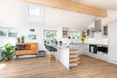 a kitchen with white cabinets and a counter top at Trevint - Modern beach house in Falmouth near beach, private garden and parking in Falmouth