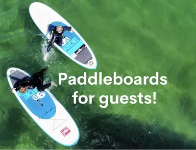 two people riding on surfboards in the water at Trevint - Modern beach house in Falmouth near beach, private garden and parking in Falmouth