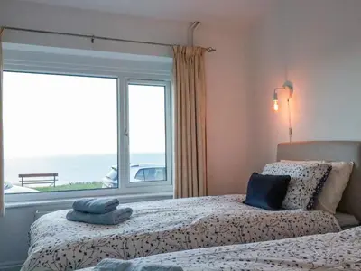 a bedroom with two beds and a window with the ocean at Sea View in Mevagissey