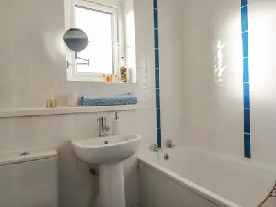 a white bathroom with a sink and a bath tub at Sea View in Mevagissey