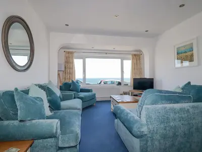 a living room with blue furniture and a large window at Sea View in Mevagissey