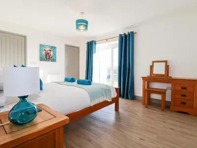 a bedroom with a bed and a table with a lamp at Bimbling Cottage in Redruth