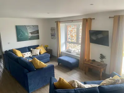 a living room with two blue couches and a window at Bimbling Cottage in Redruth