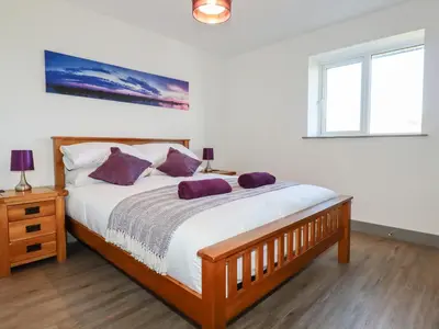 a bedroom with a bed with purple pillows on it at Bimbling Cottage in Redruth