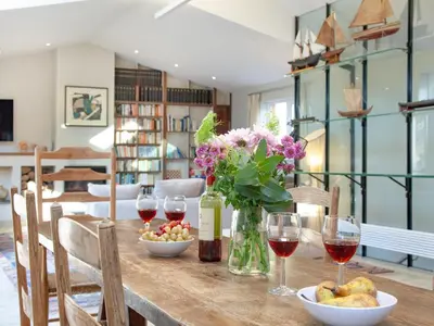 a table with glasses of wine and a vase of flowers at The Studio At Granny's Well in Fowey