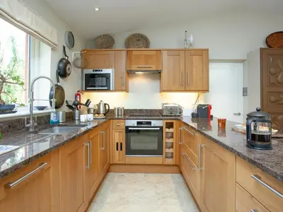 a kitchen with wooden cabinets and a counter top at The Studio At Granny's Well in Fowey