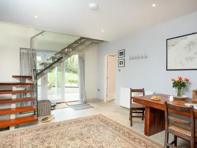 a dining room with a table and a glass staircase at The Studio At Granny's Well in Fowey