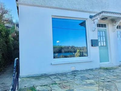 a white house with a window with a view of a lake at Waterside Victorian house at Golant Fowey in Fowey