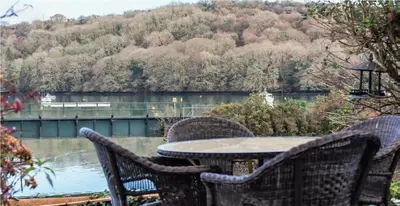 a table and chairs with a view of a river at Waterside Victorian house at Golant Fowey in Fowey
