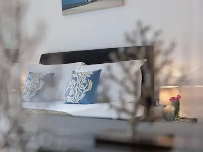 a bed with blue and white pillows and a table with a candle at Atlantis in St Ives