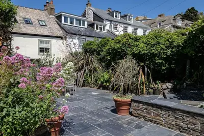 a garden with plants and flowers in front of a house at Trevan House, Port Isaac Bay Holidays in Port Isaac