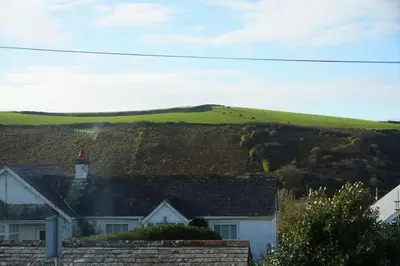 a house with a green hill in the background at Haven Cottage, Port Isaac Bay Holidays in Port Isaac
