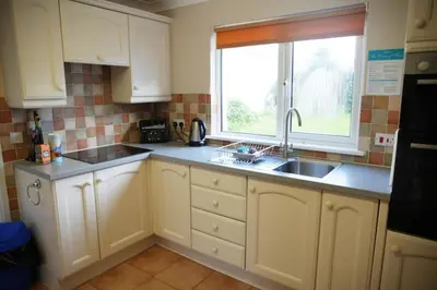 a kitchen with white cabinets and a sink and a window at Haven Cottage, Port Isaac Bay Holidays in Port Isaac