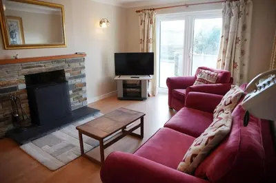 a living room with a red couch and a fireplace at Haven Cottage, Port Isaac Bay Holidays in Port Isaac